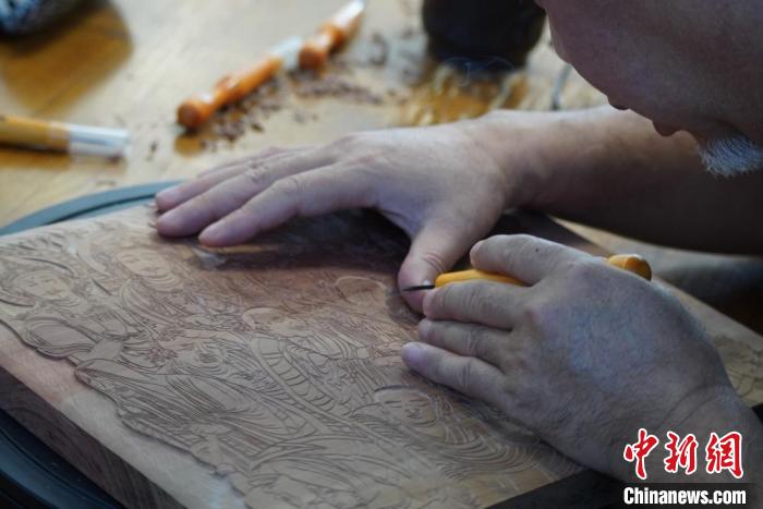 圖為徐晉林湊近木板，近距離制作雕版畫(huà)。　九美旦增 　攝
