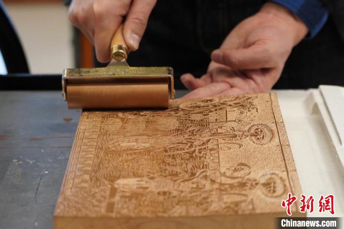 圖為徐晉林工作室工作人員正在給雕好壁畫(huà)的版面滾油墨?！【琶赖┰?　攝