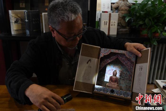 圖為讀者出版集團(tuán)讀者晉林工作室獨(dú)立出品人徐晉林，展示互動(dòng)性強(qiáng)的敦煌題材手工書。(資料圖) 楊艷敏 攝