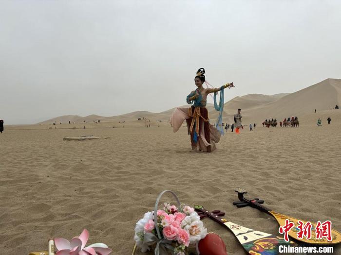圖為2023年4月底，敦煌大漠“逐舞者”奧楠在鳴沙山月牙泉景區(qū)視頻直播敦煌舞?！●T志軍 攝